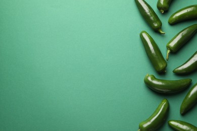 Photo of Ripe jalapeno peppers on green background, flat lay. Space for text