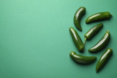 Photo of Ripe jalapeno peppers on green background, flat lay. Space for text
