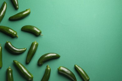 Photo of Ripe jalapeno peppers on green background, flat lay. Space for text