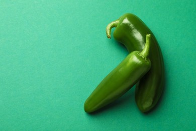 Photo of Ripe jalapeno peppers on green background, flat lay. Space for text