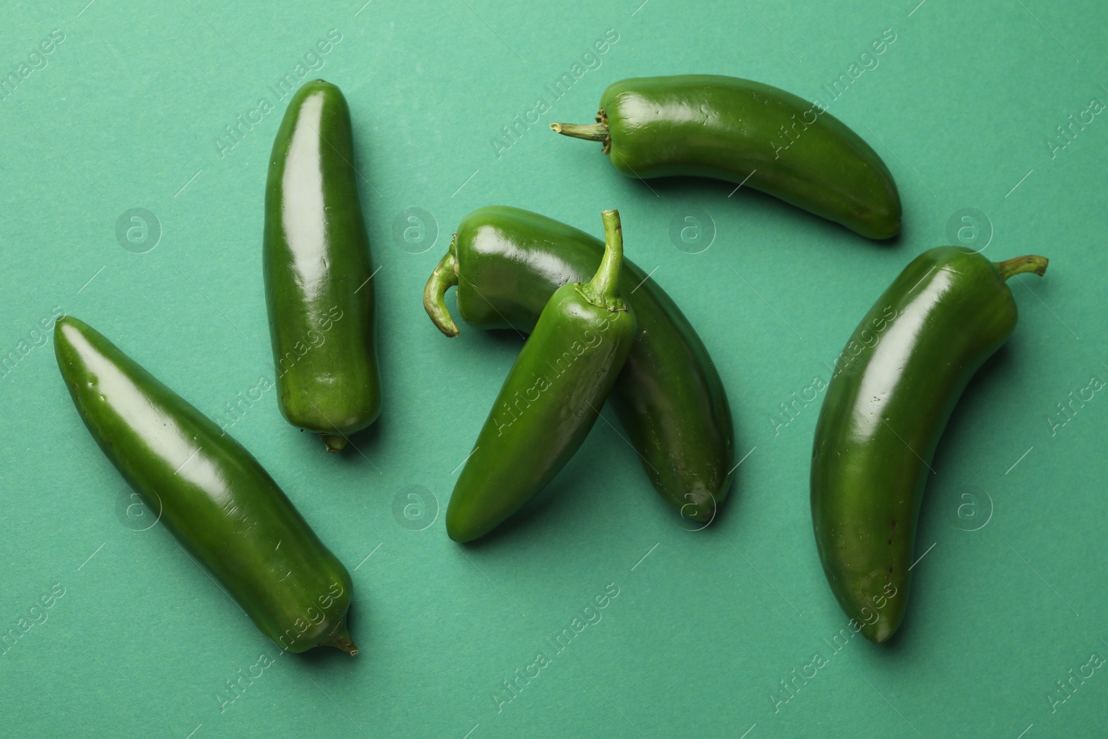 Photo of Ripe jalapeno peppers on green background, flat lay