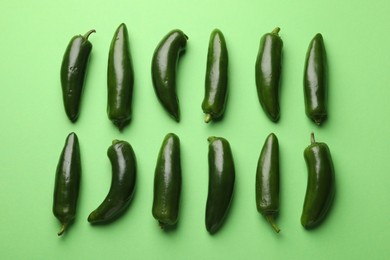 Photo of Ripe jalapeno peppers on light green background, flat lay