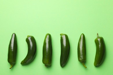 Photo of Ripe jalapeno peppers on light green background, flat lay. Space for text
