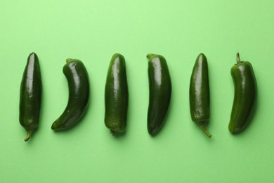 Photo of Ripe jalapeno peppers on light green background, flat lay