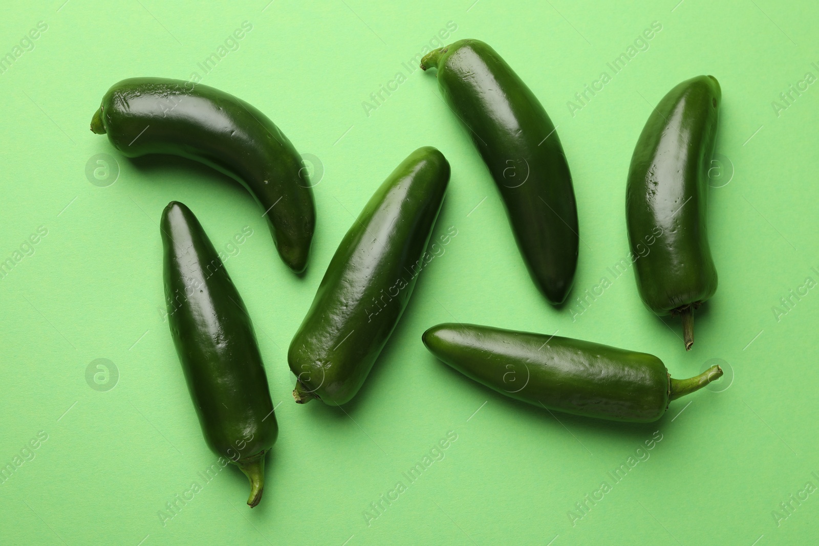 Ripe jalapeno peppers on light green background, flat lay Photo of Ripe jalapeno peppers on light green background, flat lay
