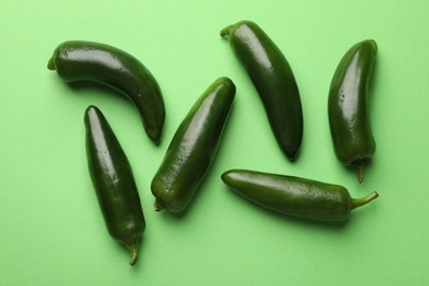 Photo of Ripe jalapeno peppers on light green background, flat lay