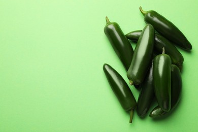 Photo of Ripe jalapeno peppers on light green background, flat lay. Space for text