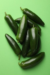 Photo of Ripe jalapeno peppers on light green background, flat lay