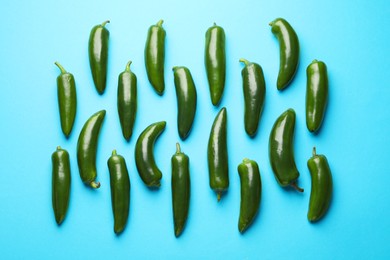 Photo of Green jalapeno peppers on light blue background, flat lay