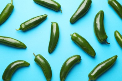Photo of Green jalapeno peppers on light blue background, flat lay