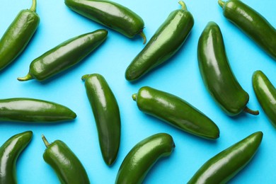 Photo of Green jalapeno peppers on light blue background, flat lay