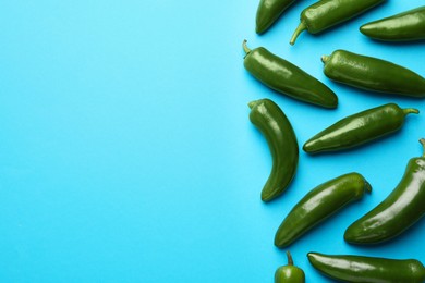 Photo of Green jalapeno peppers on light blue background, flat lay. Space for text