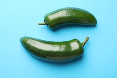 Photo of Green jalapeno peppers on light blue background, flat lay