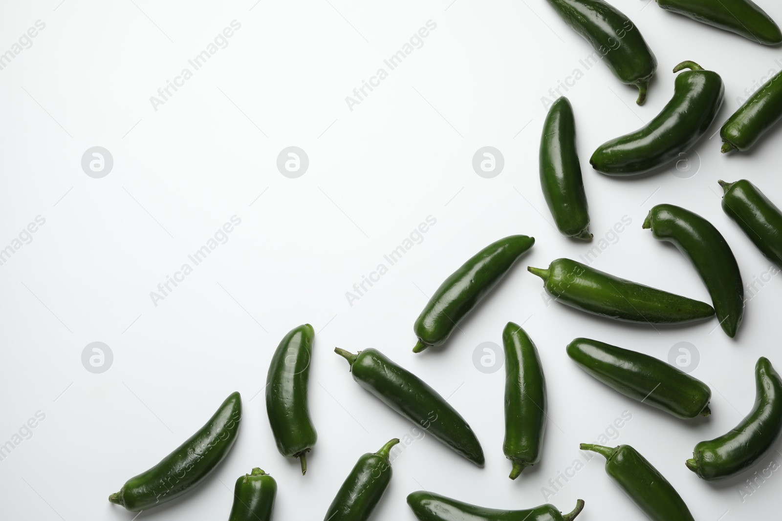 Photo of Green jalapeno peppers on white background, flat lay. Space for text