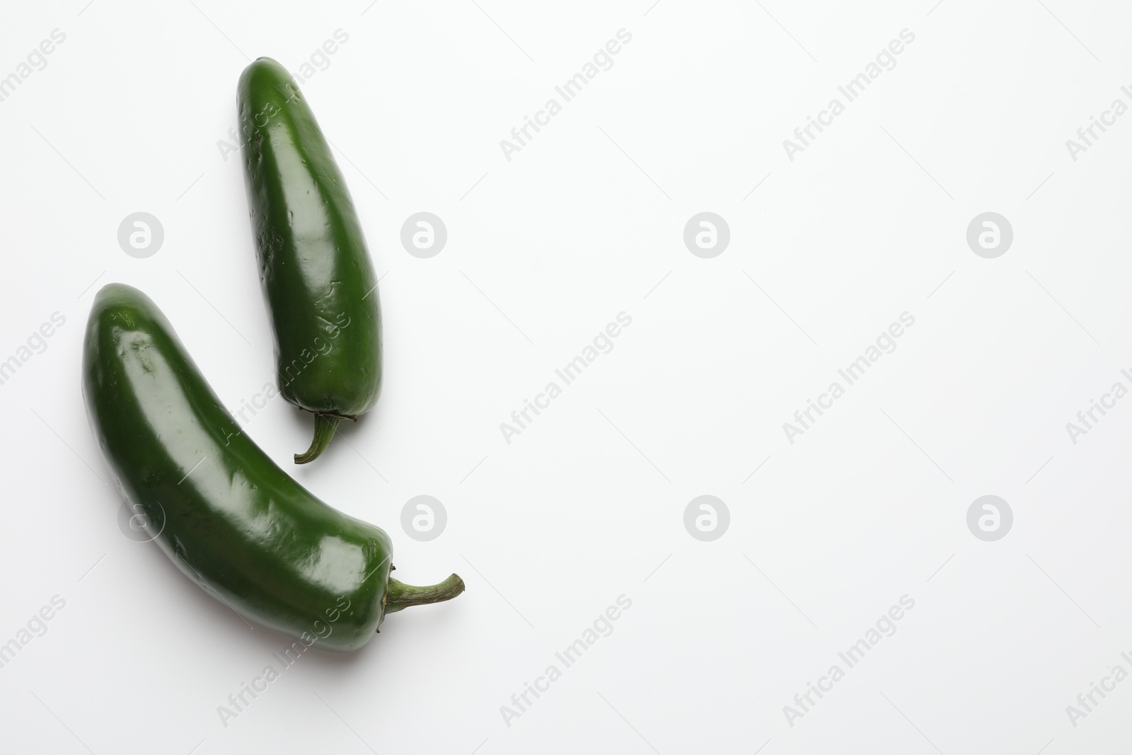 Photo of Green jalapeno peppers on white background, flat lay. Space for text