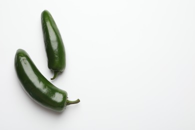 Photo of Green jalapeno peppers on white background, flat lay. Space for text