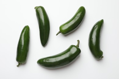 Photo of Green jalapeno peppers on white background, flat lay