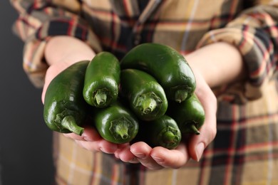 Photo of Woman with ripe green jalapeno peppers on black background, closeup