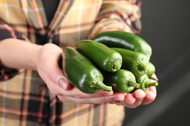 Photo of Woman with ripe green jalapeno peppers on black background, closeup