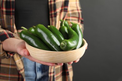 Photo of Woman with ripe green jalapeno peppers on black background, closeup