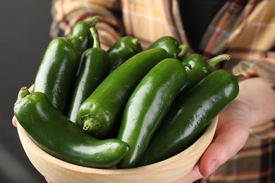 Photo of Woman with ripe green jalapeno peppers on black background, closeup