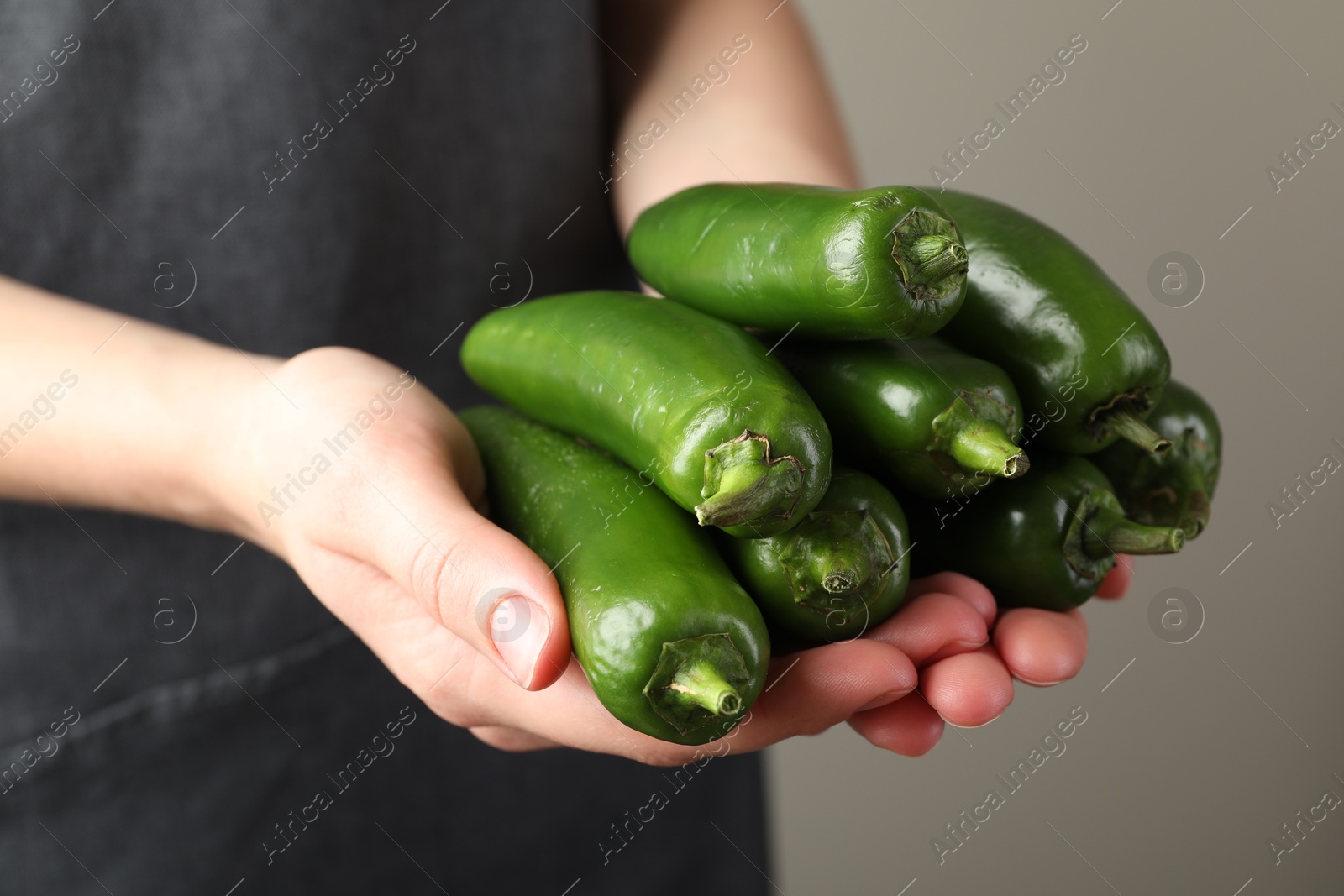 Woman with ripe green jalapeno peppers on light background, closeup Photo of Woman with ripe green jalapeno peppers on light background, closeup