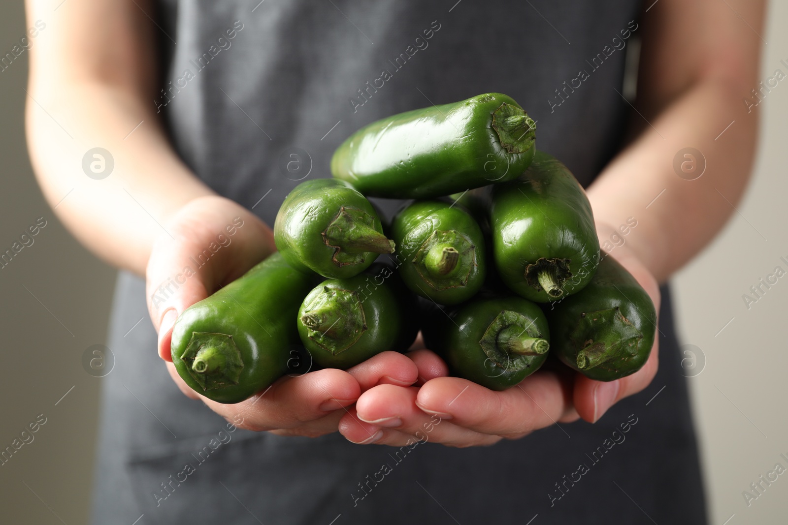 Woman with ripe green jalapeno peppers on light background, closeup Photo of Woman with ripe green jalapeno peppers on light background, closeup