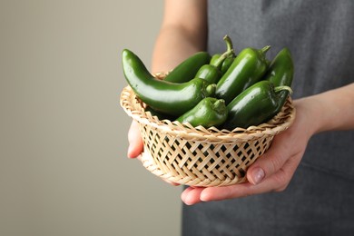 Photo of Woman with ripe green jalapeno peppers on light background, closeup. Space for text