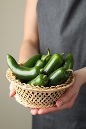 Photo of Woman with ripe green jalapeno peppers on light background, closeup