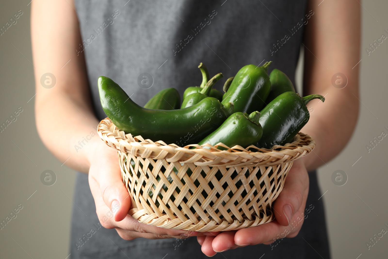 Woman with ripe green jalapeno peppers on light background, closeup Photo of Woman with ripe green jalapeno peppers on light background, closeup