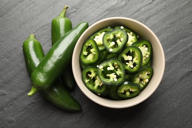 Photo of Whole and cut green jalapeno peppers on grey table, flat lay