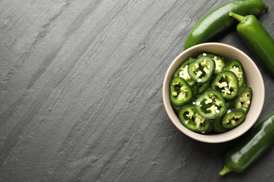 Photo of Whole and cut green jalapeno peppers on grey table, flat lay. Space for text