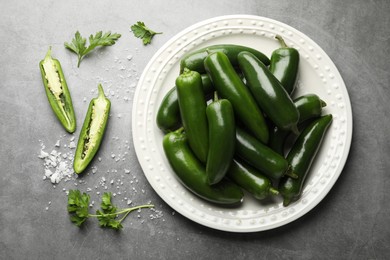 Photo of Ripe green jalapeno peppers, parsley and salt on grey table, flat lay