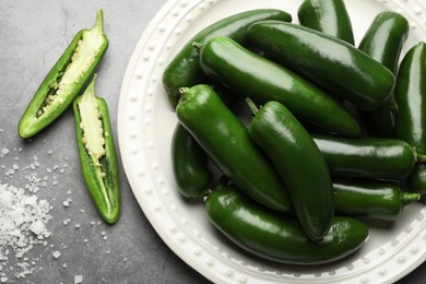 Photo of Ripe green jalapeno peppers and salt on grey table, flat lay