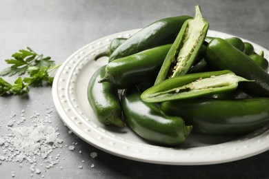 Photo of Ripe green jalapeno peppers, parsley and salt on grey table, closeup