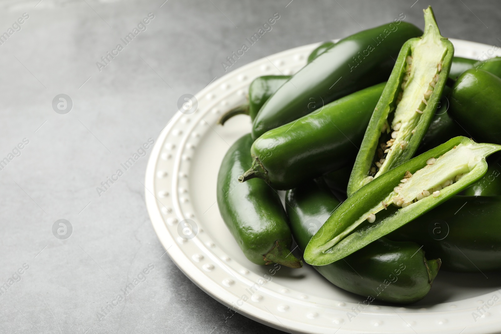 Photo of Ripe green jalapeno peppers on grey table, closeup. Space for text