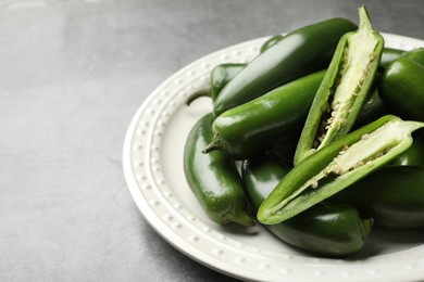 Photo of Ripe green jalapeno peppers on grey table, closeup. Space for text