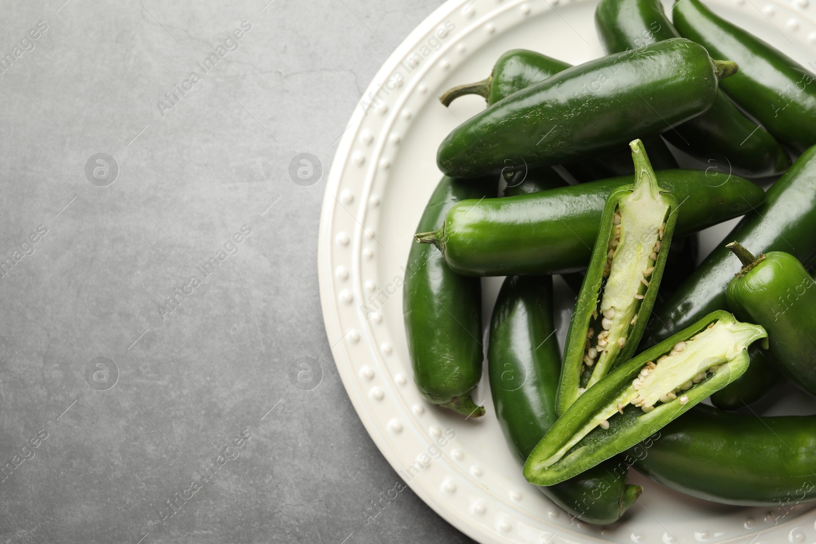 Photo of Ripe green jalapeno peppers on grey table, top view. Space for text