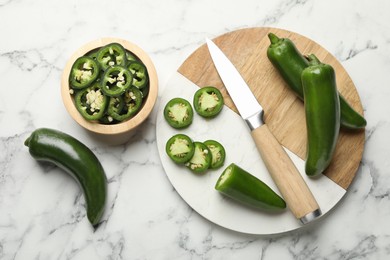 Photo of Ripe jalapeno peppers and knife on white marble table, flat lay