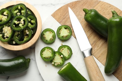 Photo of Ripe jalapeno peppers and knife on white marble table, flat lay