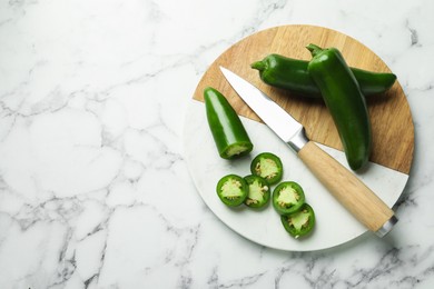 Photo of Ripe jalapeno peppers and knife n white marble table, top view. Space for text