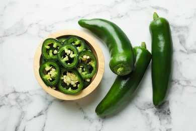 Photo of Whole and cut jalapeno peppers on white marble table, flat lay