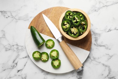 Photo of Ripe jalapeno peppers and knife on white marble table, top view