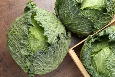 Photo of Fresh Savoy cabbages on wooden table, flat lay