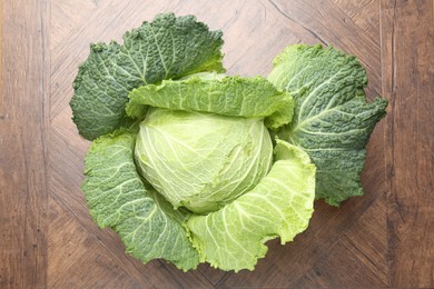 Photo of One fresh Savoy cabbage on wooden table, top view