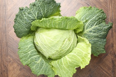 Photo of One fresh Savoy cabbage on wooden table, top view