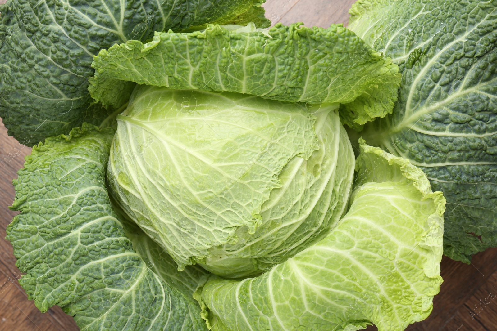 Photo of One fresh Savoy cabbage on wooden table, top view