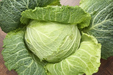 Photo of One fresh Savoy cabbage on wooden table, top view
