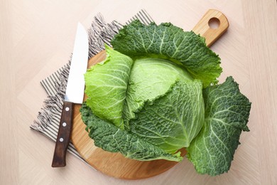 Photo of Fresh Savoy cabbage and knife on wooden table, top view