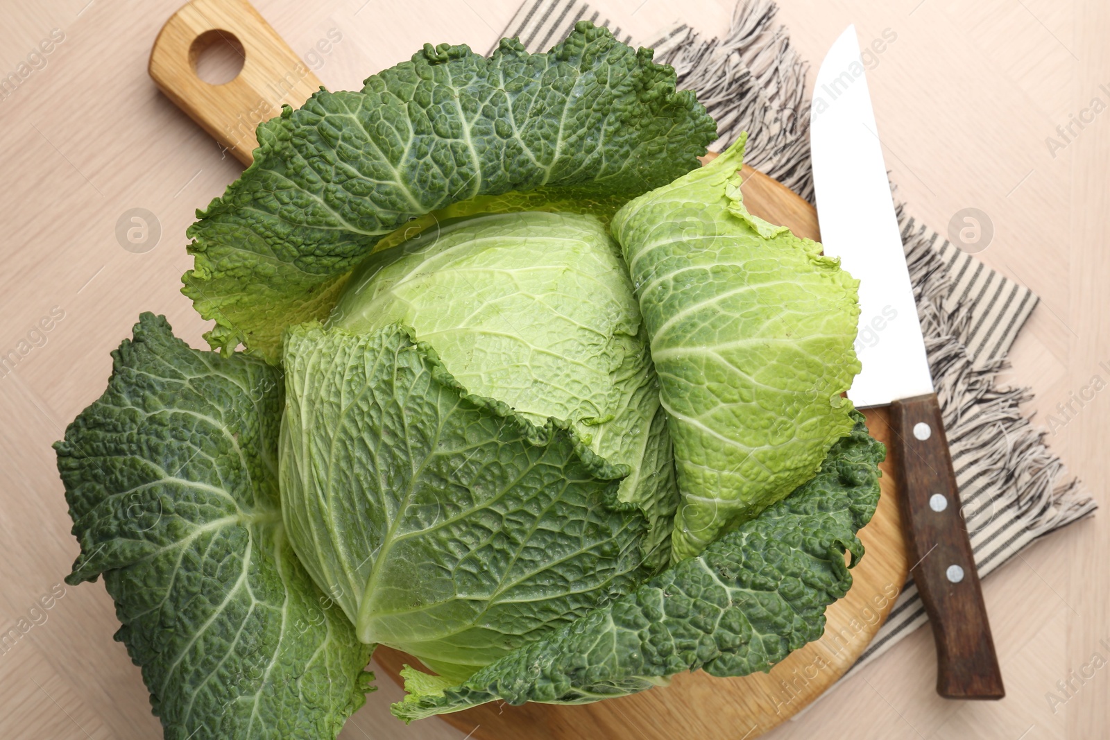 Photo of Fresh Savoy cabbage and knife on wooden table, top view